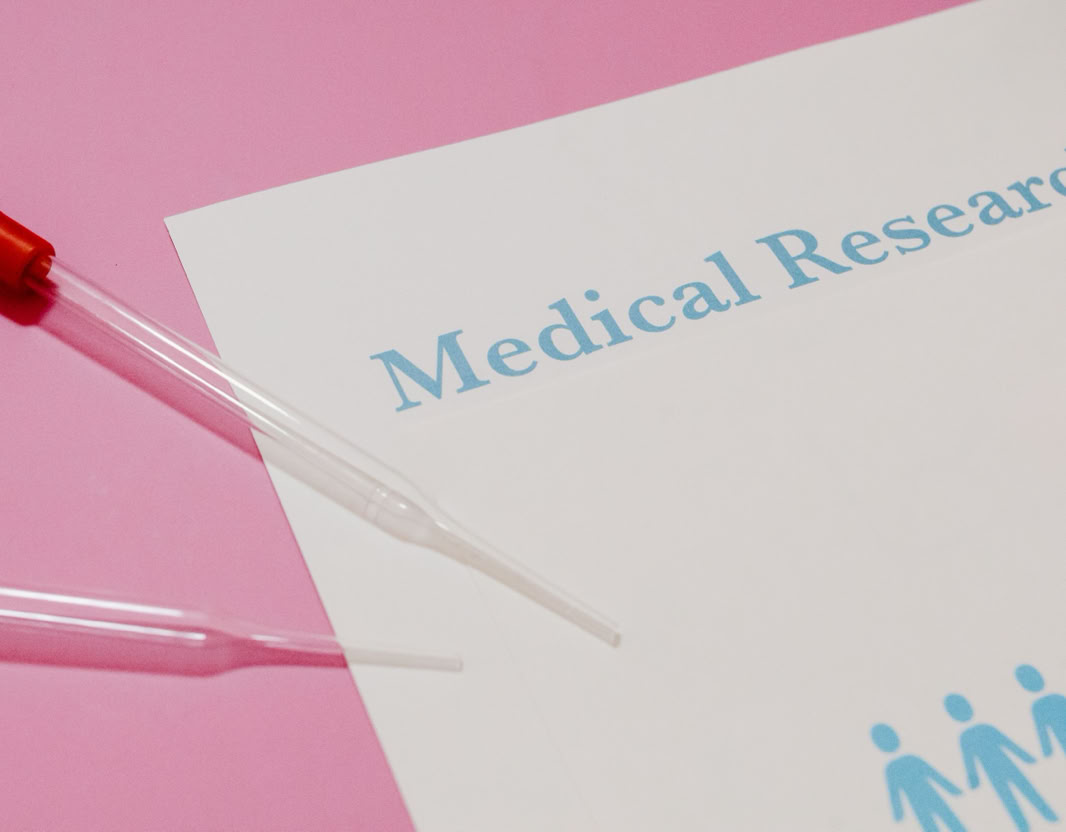Close-up of a medical research document and pipette on a pink surface, highlighting scientific research and healthcare.